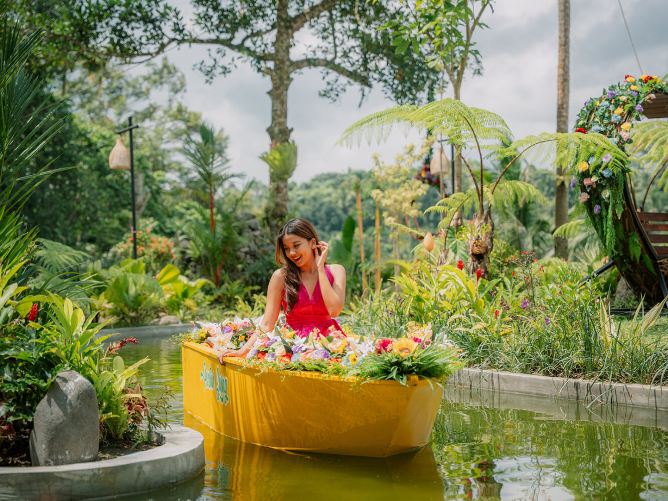 Woman enjoying a koi pond boat experience at Pertiwi Jungle Swing surrounded by tropical garden scenery